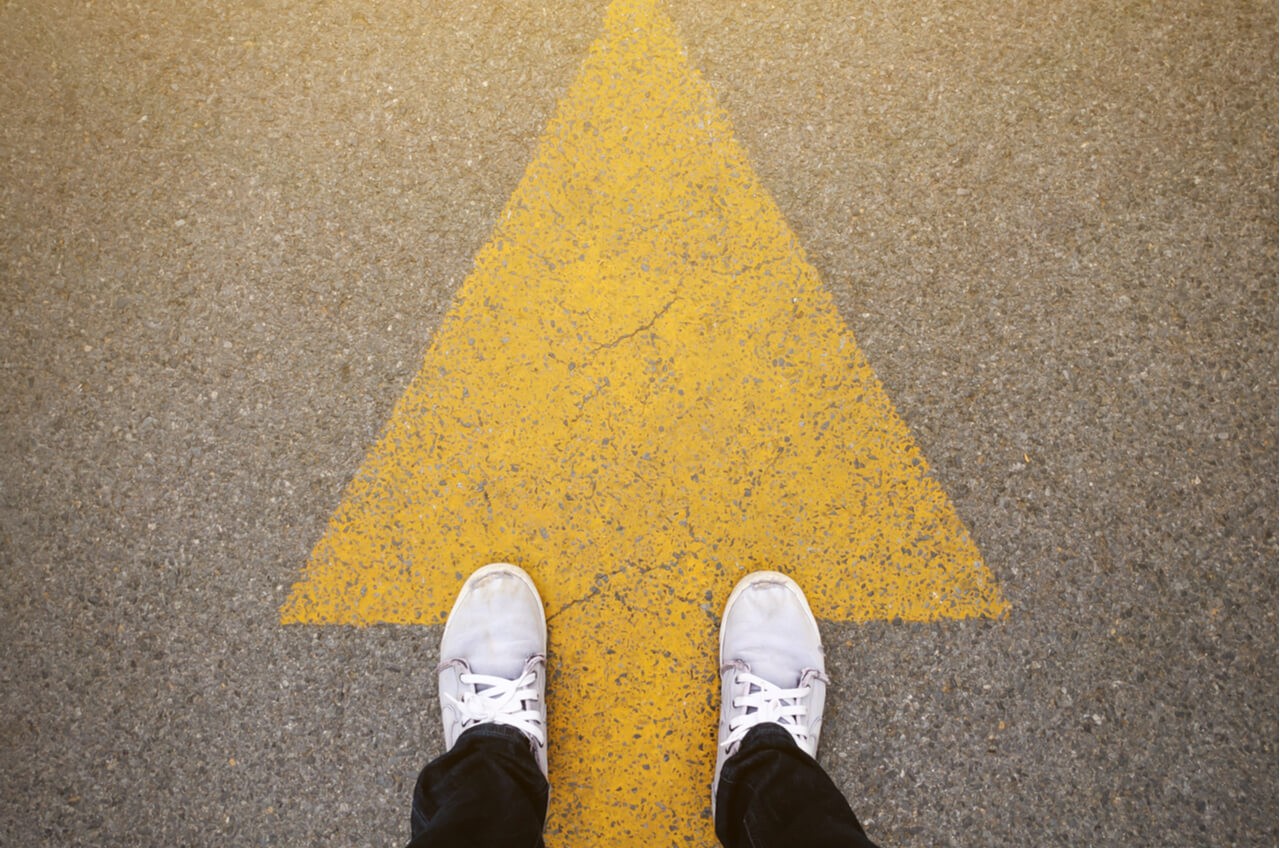 feet on painted road arrow